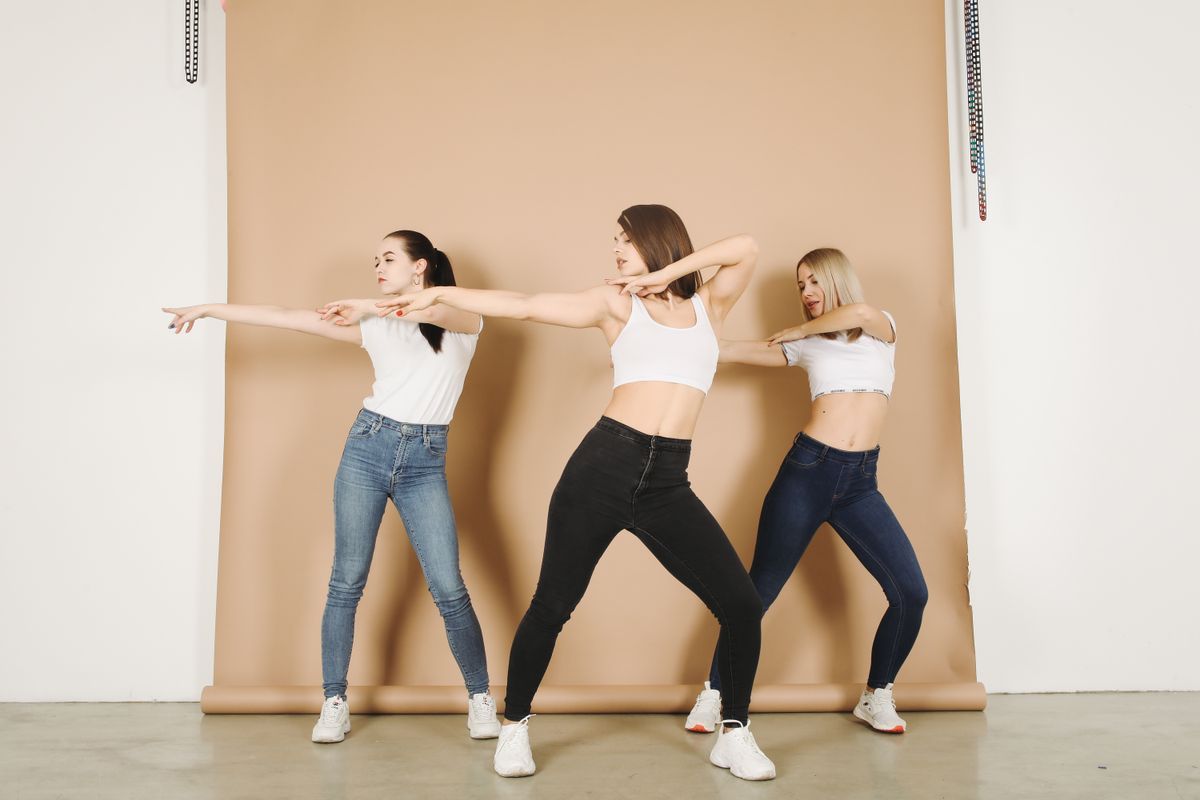ミニマルなスタジオで踊る3人の女性（K-POP）