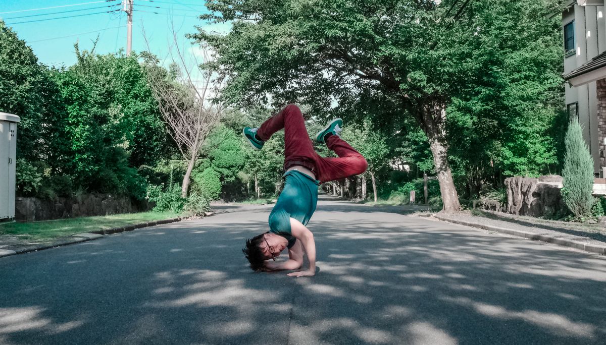 道路でヘッドスタンドをする男性